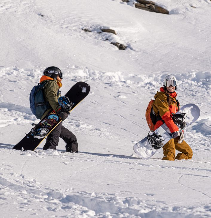 Snowboarders lopen door diepe sneeuw tijdens training